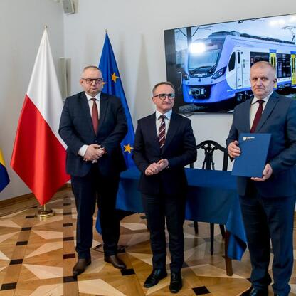 Podpis pod zdjęciem: Grzegorz Boski, wicemarszałek Województwa Śląskiego, podpisuje dokument na ceremonii podpisania umowy na zakup nowych pociągów dla Kolei Śląskich. (wygenerowano przez AI)