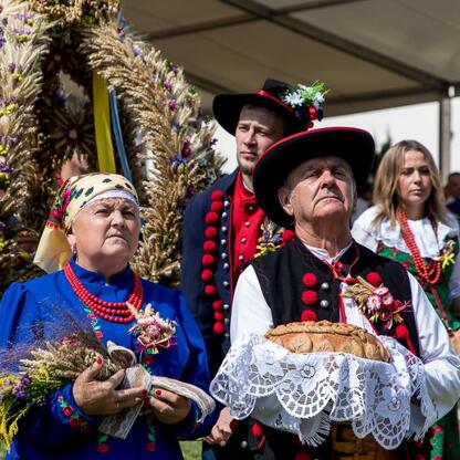 Fotografia przedstawia kolorowe festyny ludowe w tradycyjnych polskich strojach, symbolizujące kulturę i dziedzictwo regionu Śląska. (wygenerowano przez AI)