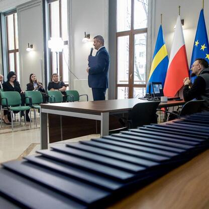 W sali konferencyjnej z flagami Polski, UE i Szwecji, przedstawiciele 42 organizacji otrzymali listy gratulacyjne, podkreślając znaczenie funduszy dla edukacji przedszkolnej. (wygenerowano przez AI)