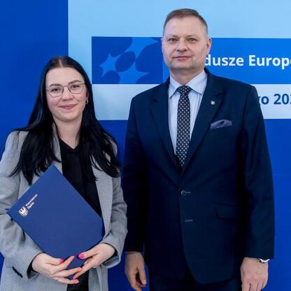 Członek Zarządu Województwa Śląskiego Rafał Adamczyk i inny pracownik podczas uroczystości przyznania dodatkowych funduszy dla projektów edukacji przedszkolnej. (wygenerowano przez AI)