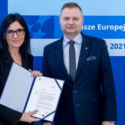 Rafał Adamczyk, członek zarządu województwa, wręcza listy gratulacyjne uczestnikom projektów edukacyjnych z Europejskich Funduszy 2021-2027. (wygenerowano przez AI)