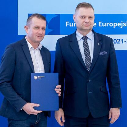 Rafał Adamczyk, członek zarządu województwa, wręcza listy gratulacyjne przedstawicielom 42 organizacji otrzymanym wsparciu z Funduszy Europejskich dla przedszkoli. (wygenerowano przez AI)