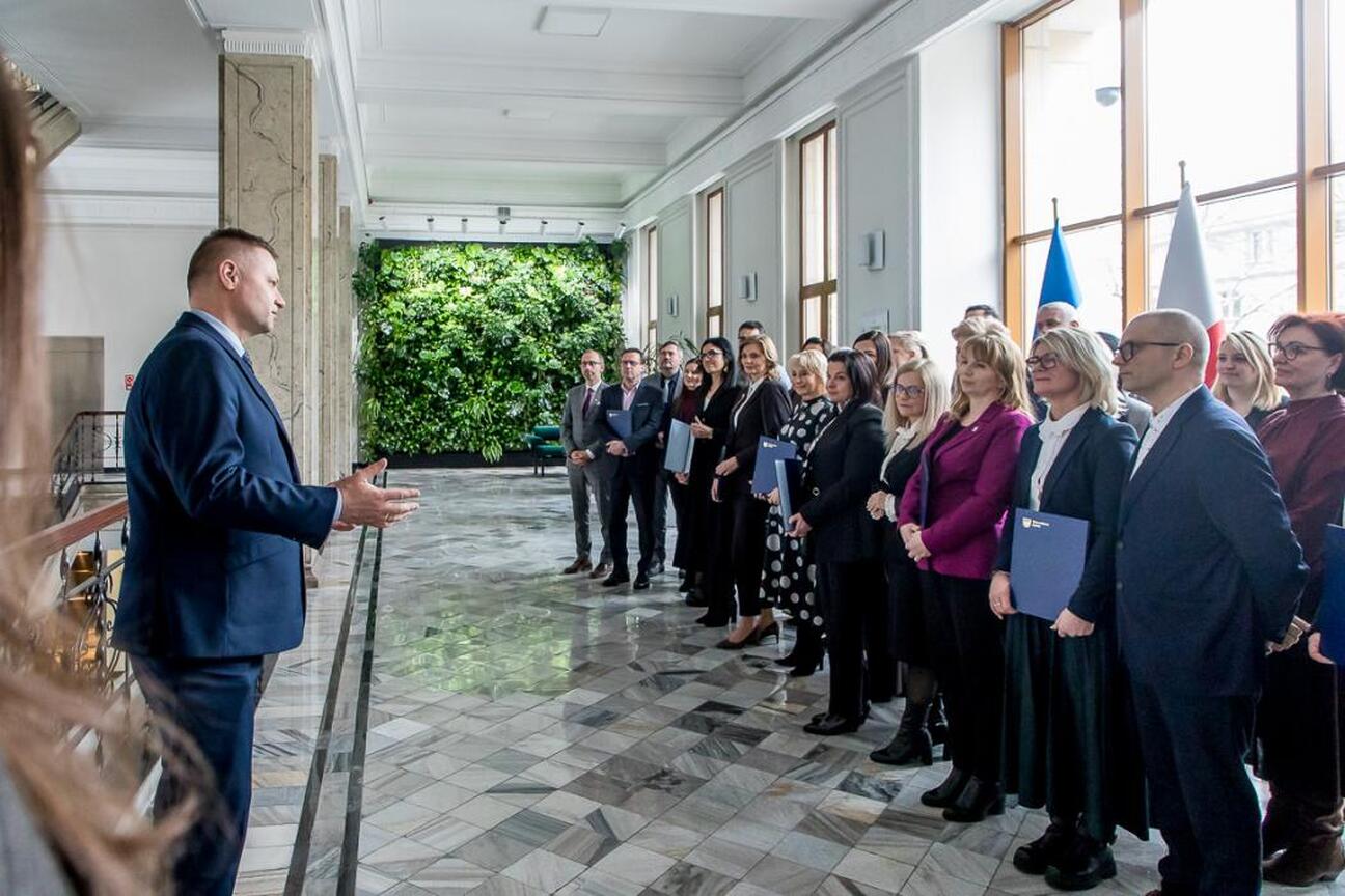 Rafał Adamczyk, członek Zarządu Województwa Śląskiego, wręcza listy gratulacyjne uczestnikom projektów edukacyjnych. (wygenerowano przez AI)
