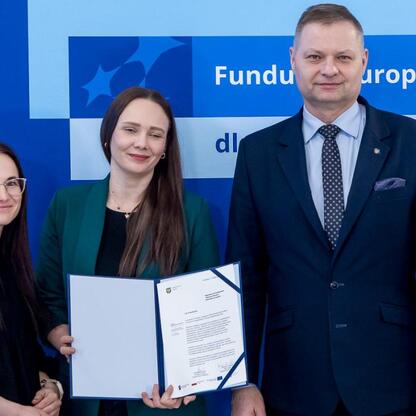 Trzech przedstawicieli projektów otrzymujących dofinansowanie z Funduszy Europejskich dla Śląska 2021-2027, podpisują dokumenty, symbolizujące formalne zatwierdzenie projektów. (wygenerowano przez AI)