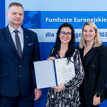 Trzech przedstawicieli organizacji stojących przed napisem 