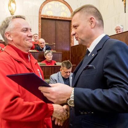 Członek Zarządu Województwa Rafał Adamczyk wręcza dyplom przewodnikowi turystycznemu w Sali Sejmu Śląskiego. (wygenerowano przez AI)