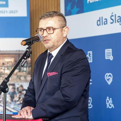 Wicemarszałek Województwa Śląskiego Leszek Pietraszek przemawia na podium podczas briefingu prasowego o programie Fundusze Europejskie dla Śląskiego 2021-2027. (wygenerowano przez AI)