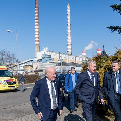 Grupa men w garniturach spaceruje wokół elektrowni, podczas wizyty w projekcie nowych bloków gazowych w Rybniku. (wygenerowano przez AI)