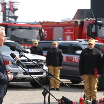 Marszałek Wojciech Saługa przemawia na ceremonii przekazania 55 specjalnych i ratowniczo-gaśniczych pojazdów dla Państwowej Straży Pożarnej w Śląskim. (wygenerowano przez AI)