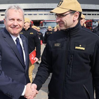 Wojciech Saługa, Marszałek Województwa Śląskiego, i Komendant Główny Państwowej Straży Pożarnej, gen. Wojciech Kruczek, podczas uroczystego przekazania 55 specjalnych i ratowniczo-gaśniczych pojazdów  (wygenerowano przez AI)