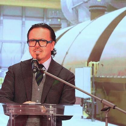 Mężczyzna w kurtce w kratę przemawia na podium podczas konferencji w Jaworznie, prezentując plan inwestycyjny TAURON dla Śląska. (wygenerowano przez AI)