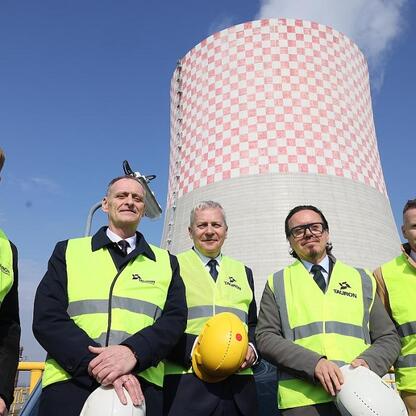 Oficjalni przedstawiciele TAURON Group na tle nowoczesnej elektrowni, podkreślając ambicje inwestycyjne dla regionu Śląska. (wygenerowano przez AI)
