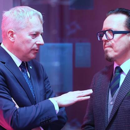 Dwóch mężczyzn w formalnym stroju rozmawiających podczas konferencji, omawiających plan inwestycji TAURON w regionie śląskim. (wygenerowano przez AI)