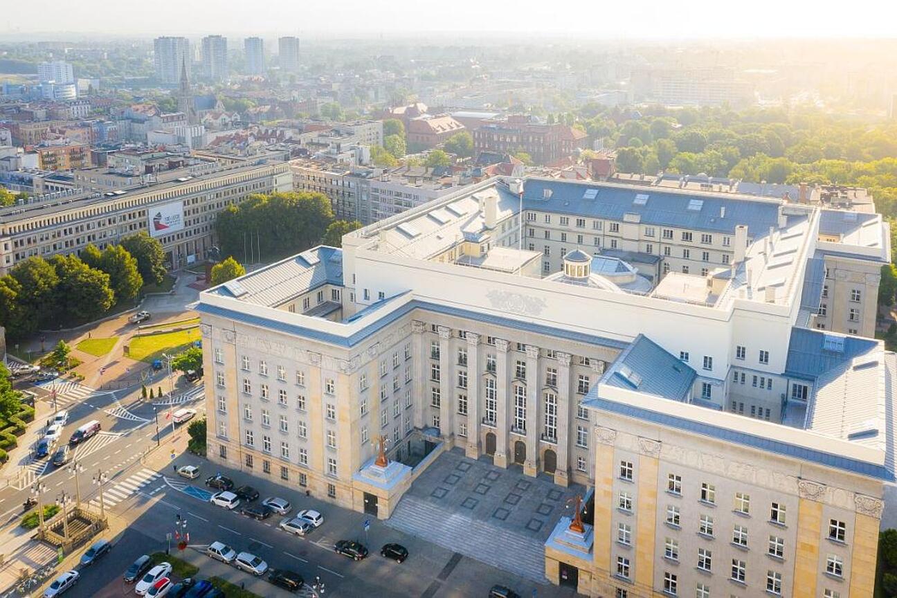 Aerial view of a grand, multi-story building with classical architecture, likely a significant public or governmental structure, situated in a bustling urban area. (wygenerowano przez AI)