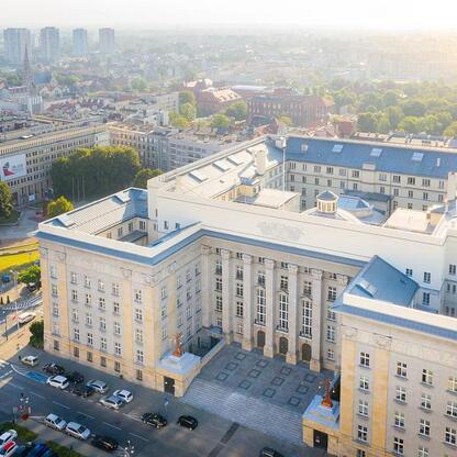 Aerial view of a grand, multi-story building with classical architecture, likely a significant public or governmental structure, situated in a bustling urban area. (wygenerowano przez AI)