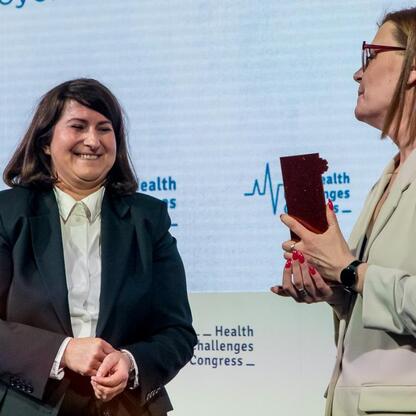 Na XI Kongresie Wyzwań Zdrowotnych dwie kobiety uczestniczą w ceremonii wręczenia nagród w IX Zdrowy Samorząd. (wygenerowano przez AI)