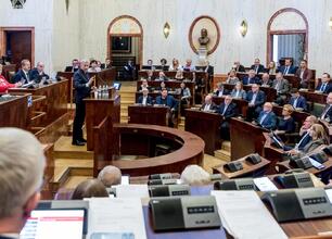 Na zdjęciu przedstawiony jest lokalny urzędnik podczas obrad Sejmiku, gdzie dyskutuje o zarządzaniu szpitalem wojewódzkim. (wygenerowano przez AI)