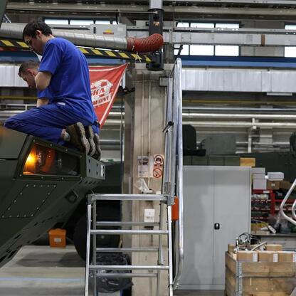 Pracownicy w fabryce montują Rosomak, modernizując produkcję. (wygenerowano przez AI)