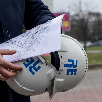 Osoba w czapce z logo Śląska trzyma plan budowy, sugerującą związanie z projektami zielonej gospodarki. (wygenerowano przez AI)