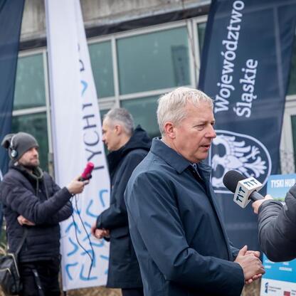 Marszałek Wojciech Saługa w rozmowie z dziennikarzem o projekcie Tyskiego Hubu Zielonej Gospodarki. (wygenerowano przez AI)
