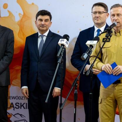 Marszałek Wojciech Saługa przemawia na konferencji prasowej w Katowicach, podczas przekazania nowych wozów strażackich dla OSP. (wygenerowano przez AI)