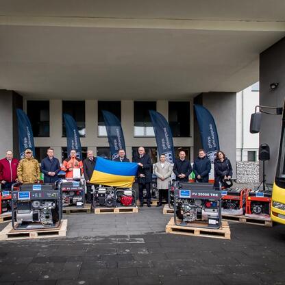 Zwolennicy wsparcia dla Ukrainy przed budynkiem, z prezentowanymi przez Województwo Śląskie agregatami prądotwórczymi i autobusami. (wygenerowano przez AI)