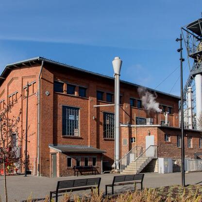 Museum of Coal Mining w Zabrzu, Polska, otwarte od 1 kwietnia, z czerwonym ceglanym budynkiem i metalową wieżą, na tle jasnego nieba. (wygenerowano przez AI)