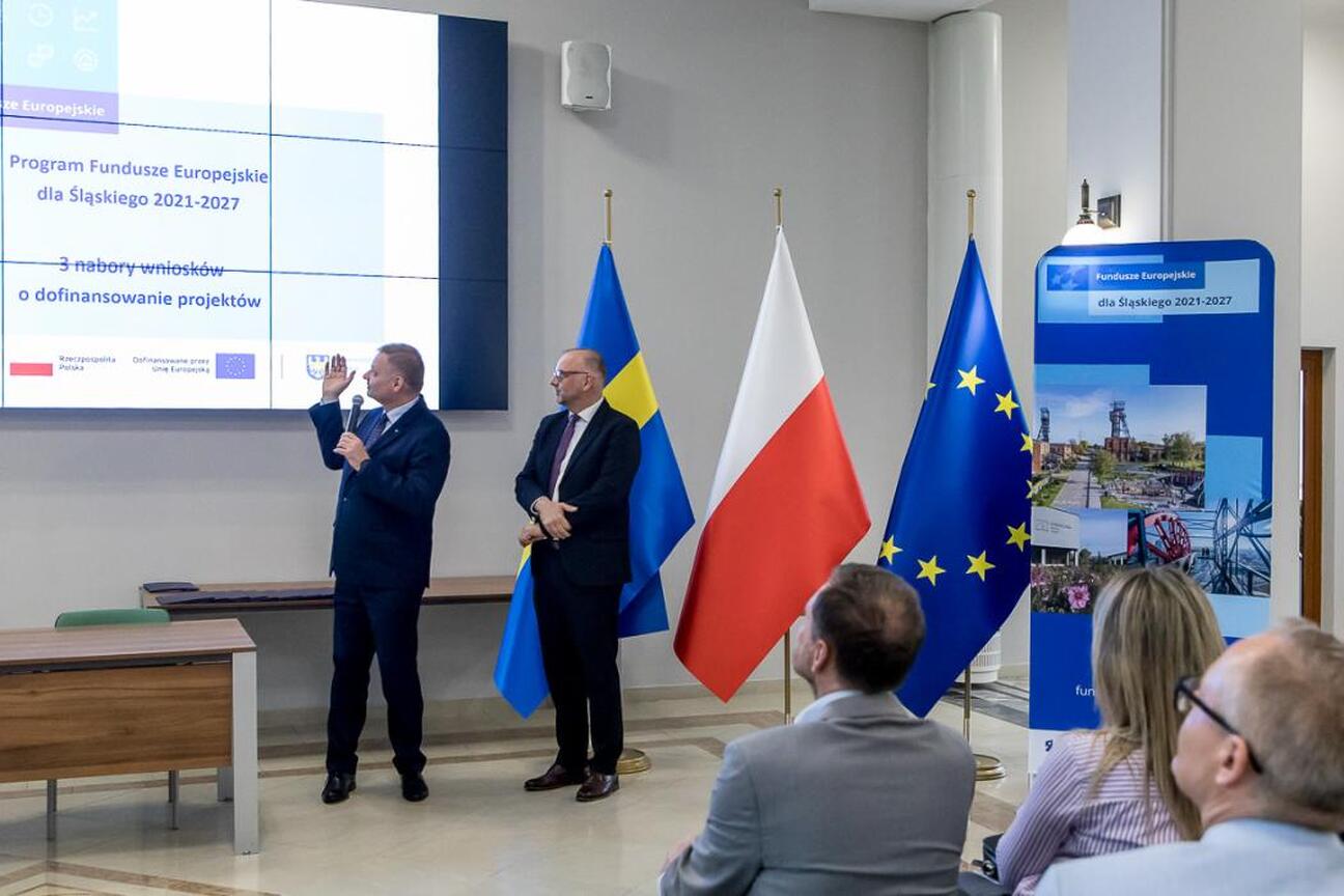 Trzech mężczyzn w strojach formalnych omawiających projekty finansowane z Europejskich Funduszy dla Śląska 2021-2027. (wygenerowano przez AI)