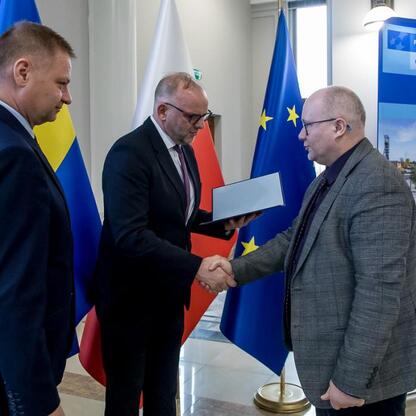 Trzech mężczyzn w garniturach podpisują dokumenty, symbolizując podpisanie umowy w ramach programu Rozwój Lokalny Kierowany przez Społeczność w Śląsku. (wygenerowano przez AI)