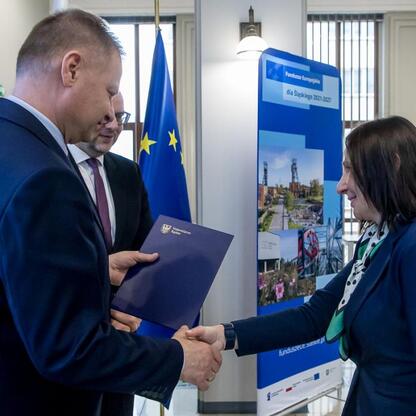 Formalna uścisk dłoni przedstawicieli administracji i partnerów finansowych w kontekście lokalnych projektów wspieranych przez Europejski Fundusz Społeczny Plus (EFS+) i Europejski Fundusz Regionalny  (wygenerowano przez AI)