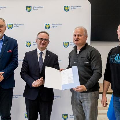 Grzegorz Boski, wicemarszałek Śląskiego, wręcza certyfikaty rodzinom ogrodnikom. (wygenerowano przez AI)