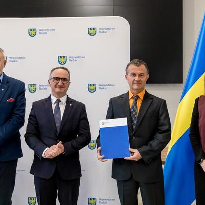 Grzegorz Boski, wicemarszałek Śląska, wręcza dokumenty na ceremonii wsparcia rodzinnych ogrodów działkowych. (wygenerowano przez AI)