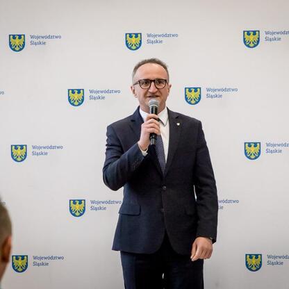 Grzegorz Boski, wicemarszałek Województwa Śląskiego, przemawia na scenie, podkreśla finansowe wsparcie dla rodzinnych ogrodów działkowych. (wygenerowano przez AI)
