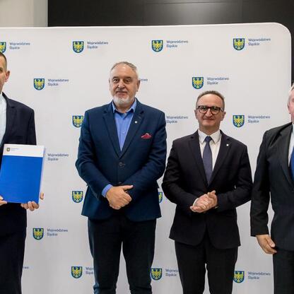 Wicemarszałek Grzegorz Boski wręcza dokumenty z funduszy na modernizację rodzinnych ogrodów działkowych. (wygenerowano przez AI)
