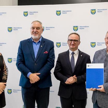 Wicemarszałek Województwa Śląskiego Grzegorz Boski wręcza dokumenty działkom podczas ceremonii wsparcia rodzinnych ogrodów działkowych. (wygenerowano przez AI)