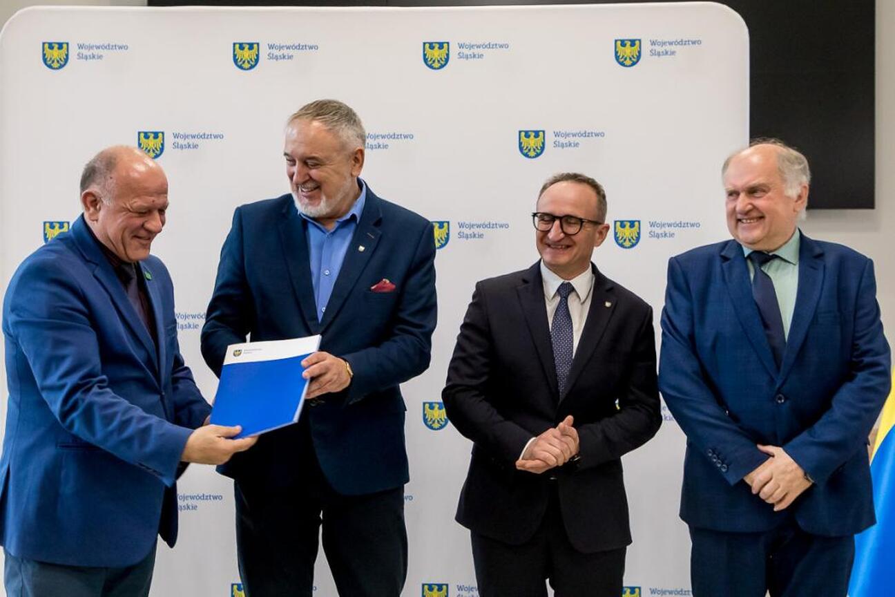 Wicemarszałek Grzegorz Boski przemawia na podium podczas uroczystości finansowej wsparcia dla modernizacji rodzinnych ogrodów działkowych województwa śląskiego. (wygenerowano przez AI)