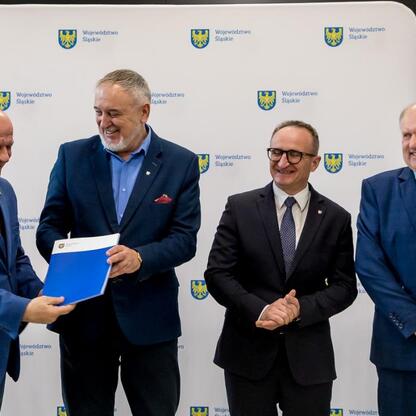 Wicemarszałek Grzegorz Boski i radny Marek Bieniek wręczają dokumenty z finansowym wsparciem dla modernizacji rodzinnych ogrodów działkowych. (wygenerowano przez AI)