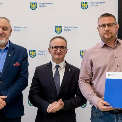 Grzegorz Boski, wicemarszałek Województwa Śląskiego, wręcza dokumenty z finansowym wsparciem dla modernizacji rodzinnych ogrodów działkowych. (wygenerowano przez AI)