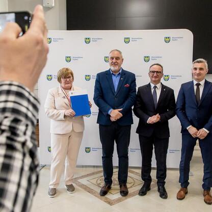 Wicemarszałek Grzegorz Boski wręcza dokumenty działkom, podczas ceremonii wsparcia ROD województwa śląskiego. (wygenerowano przez AI)