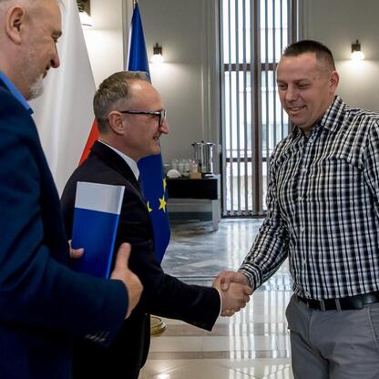 Grzegorz Boski, wicemarszałek Województwa Śląskiego, wręcza dokumenty z finansowym wsparciem dla rodzinnych ogrodów działkowych. (wygenerowano przez AI)