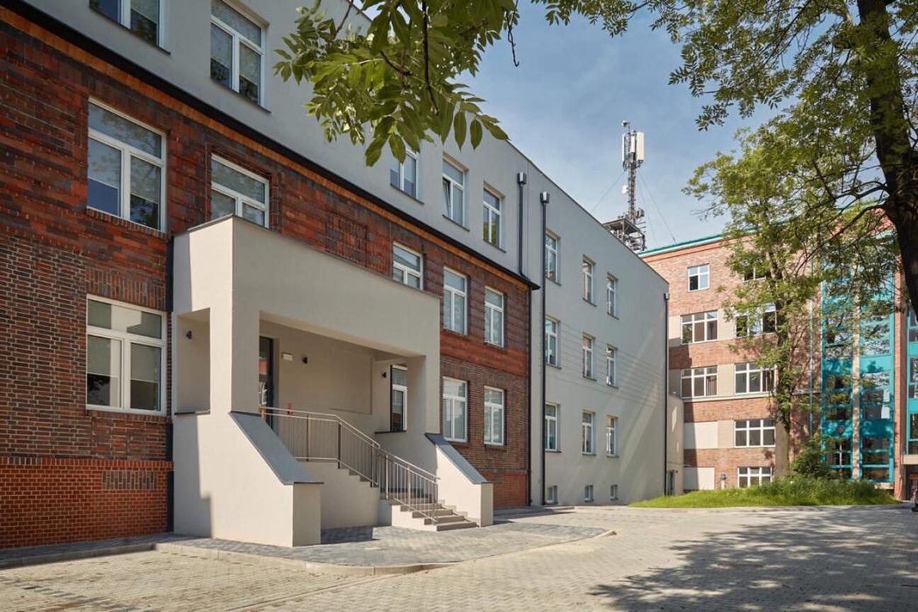 Modern hospital complex with brick and white concrete structures, featuring a staircase and courtyard. (wygenerowano przez AI)