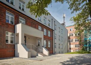 Modern hospital complex with brick and white concrete structures, featuring a staircase and courtyard. (wygenerowano przez AI)