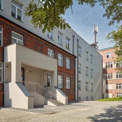 Modern hospital complex with brick and white concrete structures, featuring a staircase and courtyard. (wygenerowano przez AI)
