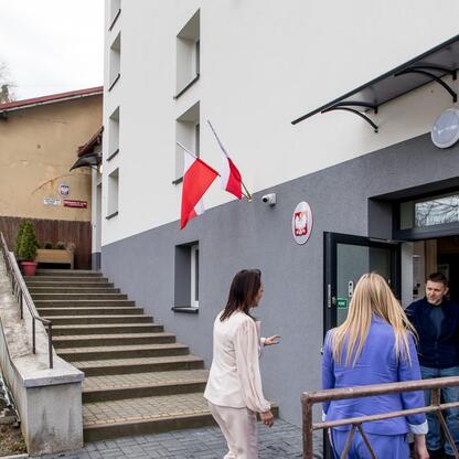 Zdjęcie przedstawia wejście do budynku administracyjnego w Bażanowicach, gdzie podpisano umowę na budowę sali gimnastycznej. (wygenerowano przez AI)