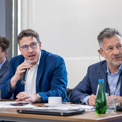 Grupa mężczyzn w rozmowie w konferencyjnym ustawieniu, wizyta delegacji Landtagu Nadrenii Północnej-Westfali w Województwie Śląskim. (wygenerowano przez AI)