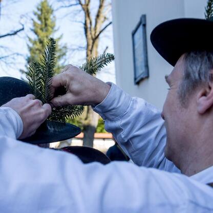 Tradycyjna inauguracja sezonu pasterskiego w Rychwałdzie, gdzie szermierz w tradycyjnym stroju ustawia gałązki na czarnym kapeluszu, symbolizującym rozpoczęcie pasterskiego sezonu. (wygenerowano przez AI)