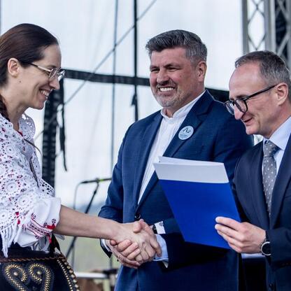 Wicemarszałek Grzegorz Boski i kobieta w tradycyjnym stroju uczestniczą w inauguracji sezonu pasterskiego w Rychwałdzie, Żywieckie, Śląskie. (wygenerowano przez AI)