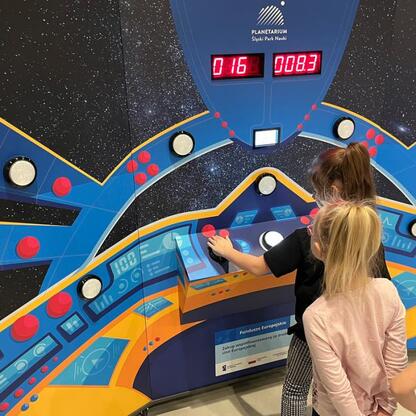 Dzieci uczestniczą w interaktywnym projekcie edukacyjnym w Planetarium Śląskim Parku Nauki. (wygenerowano przez AI)