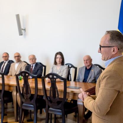 Wicemarszałek Województwa Grzegorz Boski prowadzi prezentację na konferencji w konferencyjnym pomieszczeniu, gdzie uczestnicy zwracają uwagę na rozwój pszczelarstwa i promocję miodu. (wygenerowano przez AI)