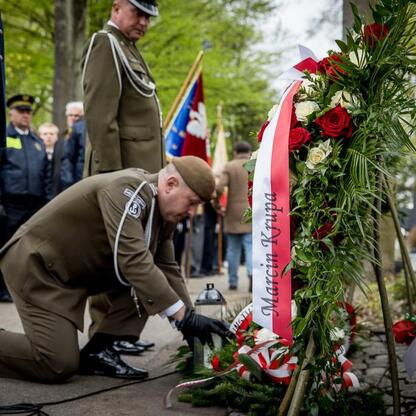 Koronowani uczestnicy uroczystości składają kwiaty na grobie Wojciecha Korfantego w Katowicach. (wygenerowano przez AI)